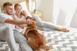 © Pixel-Shot - Happy couple with cute dog on bed at home