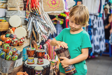 Wall Mural - Boy at a market in Ubud, Bali. Typical souvenir shop selling souvenirs and handicrafts of Bali at the famous Ubud Market, Indonesia. Balinese market. Souvenirs of wood and crafts of local residents