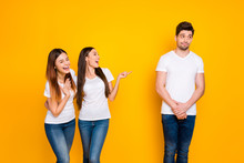 Portrait Of Excited Girls Mocking At Guy Standing Shy Wearing White T-shirt Denim Jeans Isolated Over Yellow Background