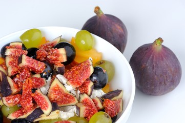 Bowl with fruit and mozarella salad and two figs on white