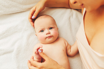 Wall Mural - young beautiful mother lies with the baby on the bed, gently kisses, sleeping together