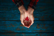 Girl holds heart in hands on blue wooden background