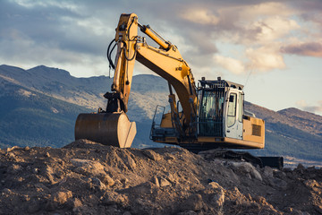 Canvas Print - Excavator on top of a dirt mound