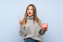 Teenager Girl With Sweater Over Isolated Blue Background Holding A Big Piggybank
