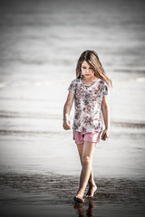 Wall Mural - beautiful young girl walking on the beach