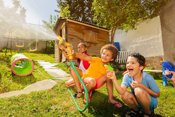 Wall Mural - Fun with water guns and garden hose sprinkler