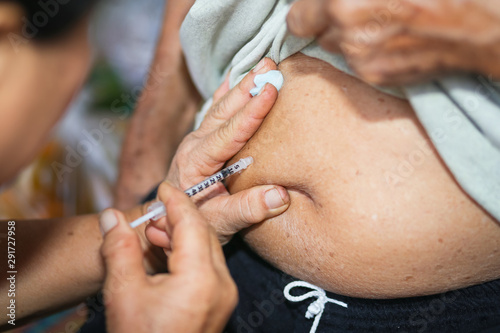 Fotografía Close up of old female hand making subcutaneous insulin injection into a diabetes patient abdomen with insulin syringe at home