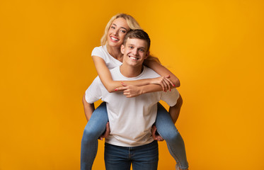 Piggyback ride. Young man carrying girlfriend on his back.