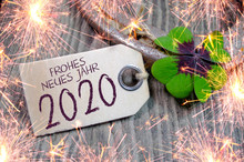 Wooden Hang Tag With Four Leaf Clover And Sparklers And With The German Words For Happy New Year - Frohes Neues Jahr 2020 On Wooden Weathered Background 
