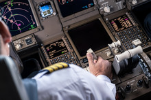 Airliner Captain Controlling Airplane In Cockpit. He Pulling Spreed Brake Lever To Slow Down The Aeroplane Speed By Right Hand. Seen Behind Pilot Seat. Modern Aviation Concept.