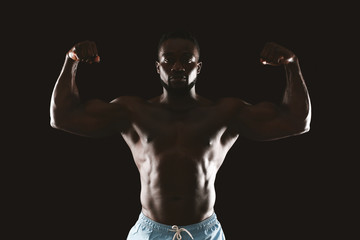 Wall Mural - Silhouette of athletic african man showing muscular biceps