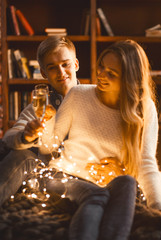 Wall Mural - man and woman drink champagne in a cozy room in the evening setting