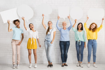 Wall Mural - Cheeful Women Holding Blank Speech Bubbles Against White Brick Wall