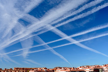 Many Chemtrails Or Contrails Produced By Airplanes Flying On Blue Sky Over The City. Conspiracy Theory Or Biological Agent