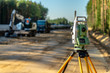 © Freedy - Surveyor engineer with equipment (theodolite or total positioning station) on the construction site of the road or building with construction machinery background