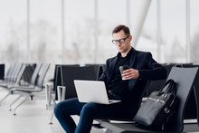 Handsome Young Businessman Working On A Laptop And Drinking A Coffee During An Expectation Of A Flight