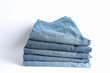 © Atlas - Stack of jeans pants on white background, space for text