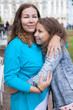 © Kekyalyaynen - Mother and pre-teen daughter embracing together in summer park, curly hair females