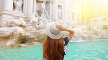 Beautiful Young Woman In Front Of Trevi Fountain At Sunset In Rome, Italy. Happy Girl Enjoy Italian Vacation Holiday In Europe.