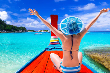 Wall Mural - Beautiful woman in a hat on a boat at the tropical island of Thailand