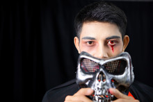 Asian Man Dressed As A Ghost And Skull Mask Handles Coming Off The Face Itself.