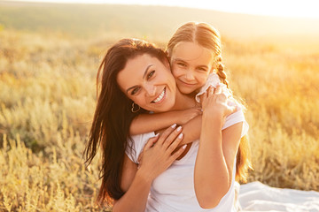 happy daughter hugging mother in meadow