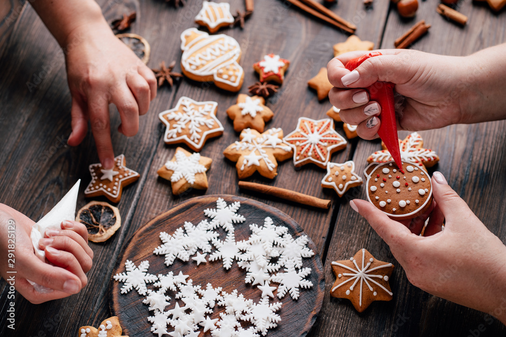 Christmas and New Year celebration traditions, festive sweets, family culinary. Traditional gingerbread. Friends decorating freshly baked cookies with icing and mastic - obrazy, fototapety, plakaty 