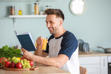 Sticker - Handsome man with book drinking juice in kitchen. Weight loss concept