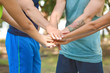 © Pixel-Shot - Group of young sporty people putting hands together outdoors