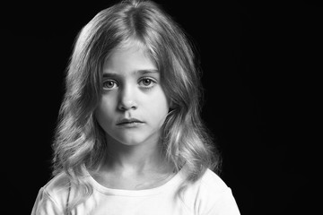 black and white portrait of sad little girl on dark background