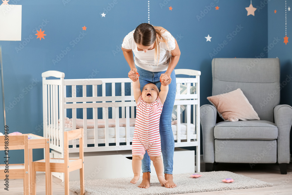 Mother teaching her little baby to walk at home
