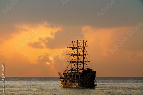 old pirate ship sailing at sea sunset