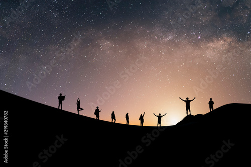 Silhouette group of tourists watch the view of star and milky way on the top of the mountain and raise their hands pointing to the stars before sunrise. We are happy to be with herself and nature.