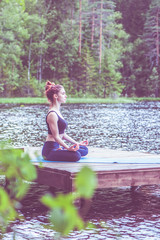 Wall Mural - Yoga meditation  by Young yogi  girl  on the pier of a beautiful lake.  The concept of appeasement,  healthy lifestyle.