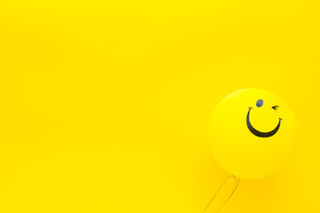 Wall Mural - Happiness emotion. Yellow balloon with smile on yellow background top view copy space