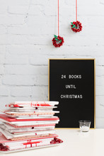 Pile Of Books Wrapped In Paper Close To Board Saying ""24 Books To Christmas""
