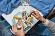 © Yaroslav Danylchenko/Stocksy - The girl's hands hold a fork and an open fresh oyster on the background of plates with lemon slices, oysters and a glass of wine on the table with a blue tablecloth. Dinner at the restaurant