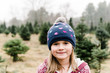 © Léa Jones/Stocksy - portrait little girl in big woolly hat in Christmas tree farm