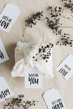 Privet Branches With Berries And Gift Cards Surround A Present Wrapped Inside Cotton Napkin