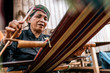 © Santi Nunez/Stocksy - Cheerful elderly woman weaving on street