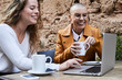 © Ivan Gener/Stocksy - Happy women using laptop terrace bar.
