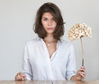 © papa - Portrait of a young beautiful woman in a white shirt with a dry hydrangea flower in her hand.