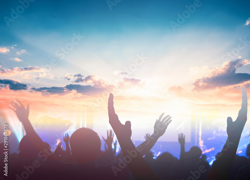 Worship and praise concept: christian people hand rising on sunset background