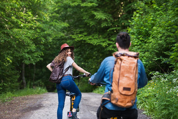 Wall Mural - rear view of young tourist couple travellers with electric scooters in nature.
