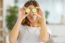 Playful Woman Covering Her Eyes With Slices Of Cucumber