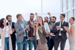 © ASDF - happy young woman standing in front of her jubilant colleagues