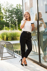 Sticker - Business lady with cup of coffee talking by mobile phone.