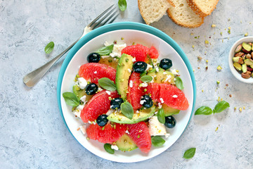 Avocado salad with grapefruits, feta cheese, black olives and pistachio. Top view with copy space. Healthy eating.