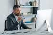 © LIGHTFIELD STUDIOS - handsome businessman in formal wear holding glasses and looking at computer