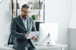 © LIGHTFIELD STUDIOS - handsome businessman in formal wear using digital tablet in office